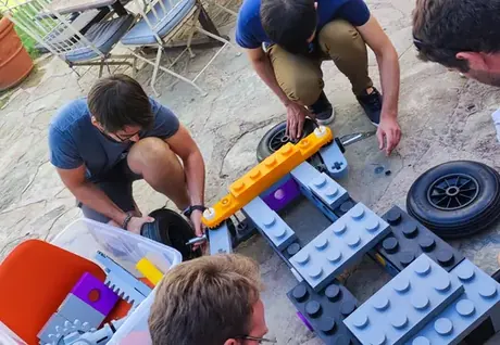 Compañeros montando un coche con bloques gigantes al aire libre