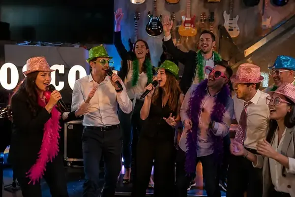Compañeros cantando en el escenario durante un concurso musical de empresa